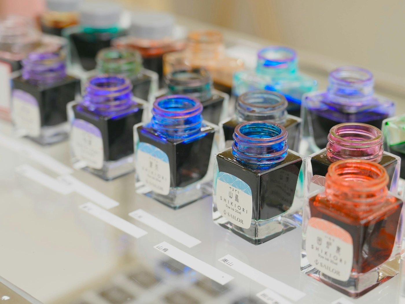 A shelf of small bottled inks in graded colours.