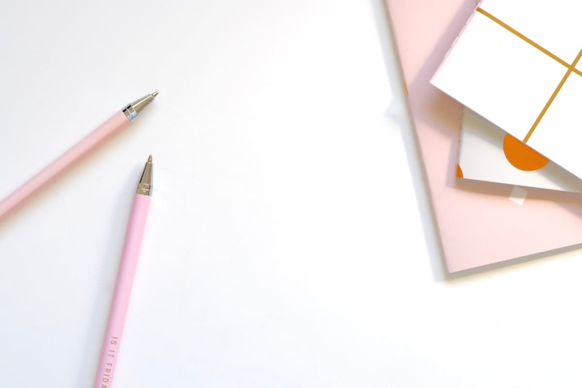 Two pens resting on an open notebook.